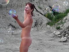 naked mature woman toys with soap bubbles